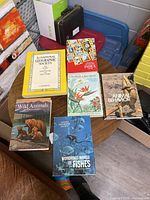 Six hardcover National Geographic books on a round table showing colorful covers with wildlife, fish, wildflowers, and text
