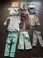 Full lot of girls clothing showing all tops and bottoms arranged on floor