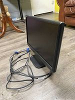 Side view showing the screen and attached VGA and power cables coiled beside the monitor.