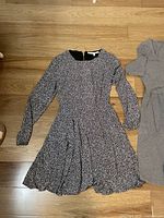 Black and white floral long-sleeve dress laid flat on wooden floor.