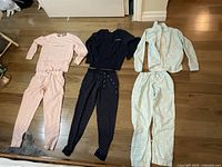 Three pajamas for girls/teens laid out on wood floor: pink Calvin Klein set, navy blue Calvin Klein set, pale green Vie De Rose set