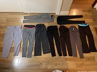 Full view of nine pairs of pants and tights laid flat on floor showing color, style and length variations