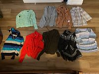 Overview of all 9 sweaters laid out on floor showing variety of colors and styles.