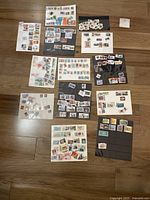 An overview of the stamp collection showing multiple white and black presentation cards with Canadian stamps spread on a wooden surface.