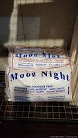 Photo of stacked Moon Night pillows in original plastic packaging, showing brand name and product details.