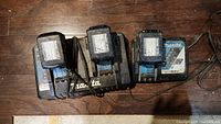 Overhead view of three batteries mounted on dual charger on wooden floor
