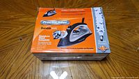 Closed box of Proctor Silex iron with orange and white packaging showing image and details.