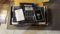 Top-down view of Numark NS6 DJ controller inside original box with user manuals on top.