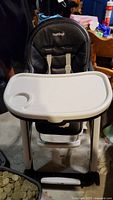 Full view of the Peg Perego baby high chair with attached white tray and padded black seat.