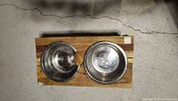 Top-down view of the raised dog bowl stand showing two stainless steel bowls in a wooden frame made from recycled wood.
