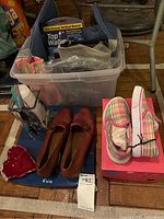 Photo of plastic bin with bags, shoes, and personal care items on floor
