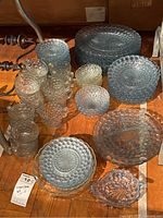 Top down view of the bubble glass plates, cups, bowls, and serving pieces arranged on wood floor.