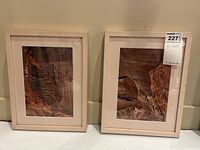 Photo showing two custom framed red rock photographs side by side with blush pink frames and mat boards, glass fronts smudged and dusty.