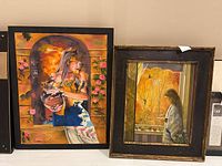 Two framed paintings side by side: on the left 'Girl in Window' by Dan Cord showing a woman with butterflies, on the right a painting by Angel Latorre showing a girl gazing out a window.