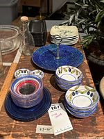 Overview of assorted decorative dishes and plates including olive dishes, blue glass saucers, rectangular plates, and clear bottle.