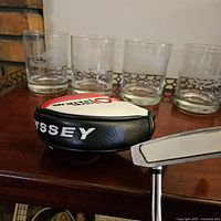 Photo showing four clear glass tumblers on a wooden surface, each with images of famous golf hole designs.