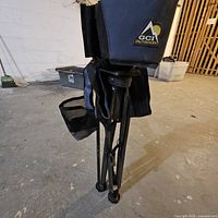 Close-up of black folded stool frame with GCI Outdoor logo visible on fabric.