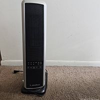 Front view of a tall black and white Lasko electric room heater on carpet.