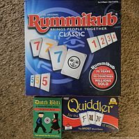 Photo showing the box covers of three classic table games included in the lot: Rummikub Classic, Dutch Blitz, and Quiddler.