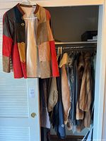 Full closet showing patchwork leather jacket at front with assorted coats behind