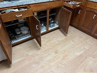 Wide shot of open lower kitchen drawers and cabinets revealing cookware and utensils inside.