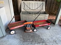 Photo showing two red Radio Flyer wagons side by side and a large chest freezer in the background with the lid open