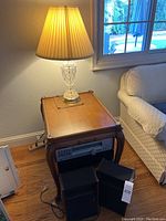 Side table with crystal lamp on top next to couch and window