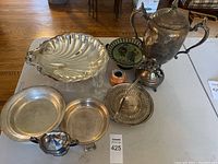 Photo showing entire bundle of silver plate items including teapot, sugar bowl, serving trays, glassware, and decorative plates.