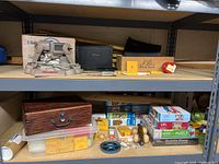 Shelf of assorted vintage games, puzzles, and film equipment components