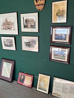 Photo showing a wall displaying multiple framed historical photographs and prints related to Campbell and San Jose local history including cars, banks, courthouse.