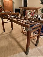Wood folding tub bench with wire hanger, wire frame hanging piece, and birch bark canoe shown on bench indoors.