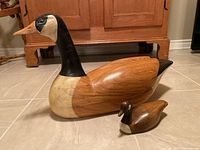 Both decoys together on floor against wooden cabinet
