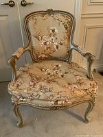 Front view of the floral upholstered wood frame armchair with carved anemone details and Queen Anne legs.