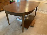 Full angle view of oval wooden dining table with smooth tabletop and tapered legs.