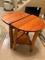 Front view of one pine side table showing the roundish plank top and tree branch legs.