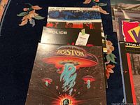 Photo shows top 4 records in stack: The Police - Synchronicity, Boston, and others.
