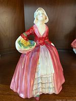 Front full view of Royal Doulton Janet figurine in red-pink dress holding basket