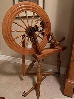 Wide angle photo showing entire spinning wheel and stand, highlighting wooden structure and general condition