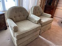 Pair of beige/olive patterned velveteen tub chairs with loose removable cushions, positioned side by side near window with natural light.