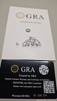 Photograph of the GRA Moissanite certification report with the Moissanite gemstone placed on the card.
