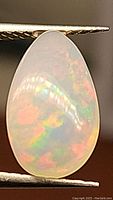 Close-up photo of the pear-shaped Ethiopian opal cabochon showing rainbow flashes of color within the opal.