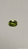Close-up of oval cut apple green peridot gemstone showing bright green color and faceted cut
