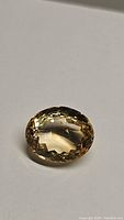 Close-up photo of the natural golden citrine oval cut gemstone showing its faceted surface and golden yellow color.
