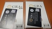 Pair of certified moissanite earrings with GRA certificate cards included, showing authentication and grading details.