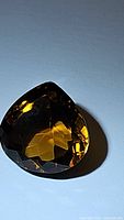 Close-up photo of pear cut cognac colored Madeira Citrine gemstone showing facets and color.