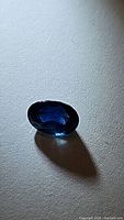 Oval faceted sapphire on white background showing table and depth of color