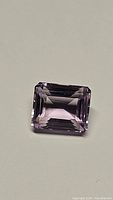 Close-up photo of the natural fancy purple pink amethyst gemstone showing its emerald step cut and transparency.