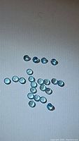 Clear photo showing 22 natural sky blue topaz gemstones arranged on white surface to display size and color.