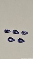 Five pear cut natural tanzanite gemstones shown from angle highlighting the cut and color.