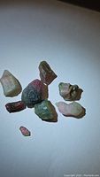 Eight natural rough watermelon tourmaline crystals with pink and green hues shown from overhead on a white background.